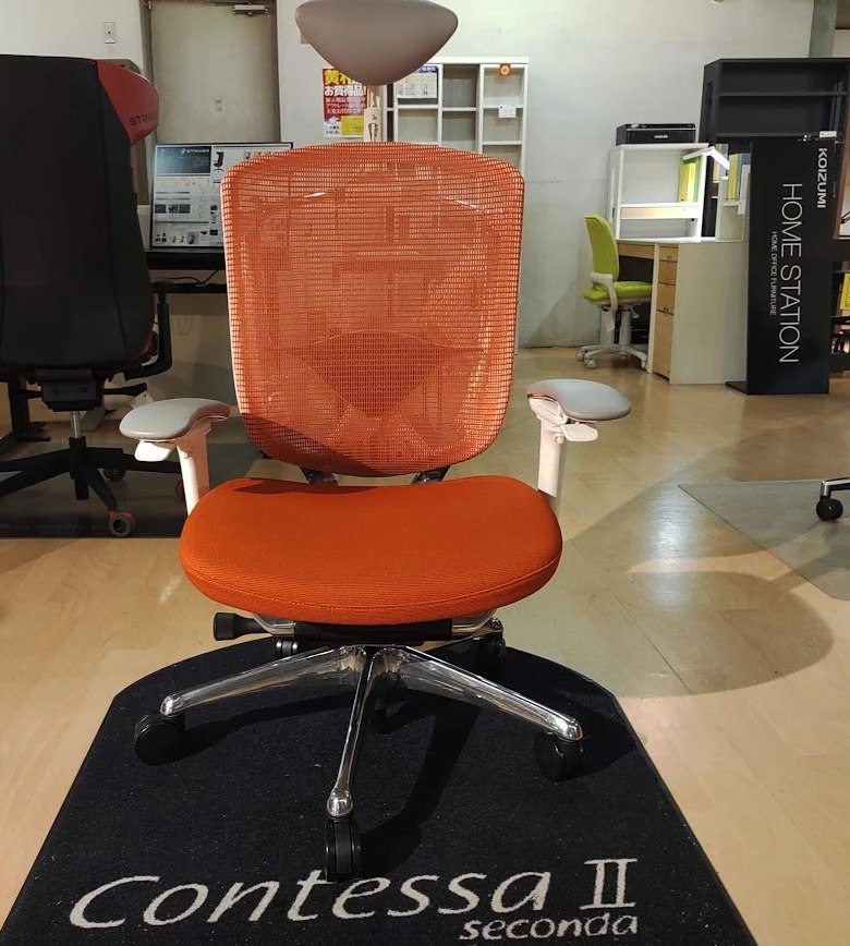 家具店に展示されていたオカムラ コンテッサ セコンダを正面から(オレンジのメッシュの背もたれ・クッション座・ヘッドレスト付き)