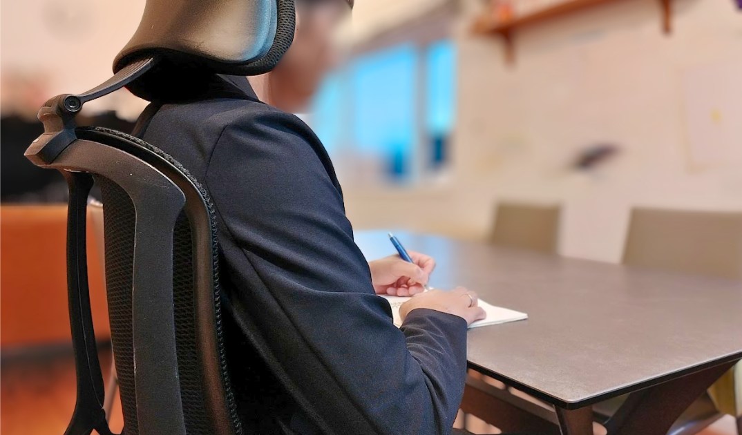 オカムラ シルフィーを前傾にして、テーブルでノートにペンで書いている様子